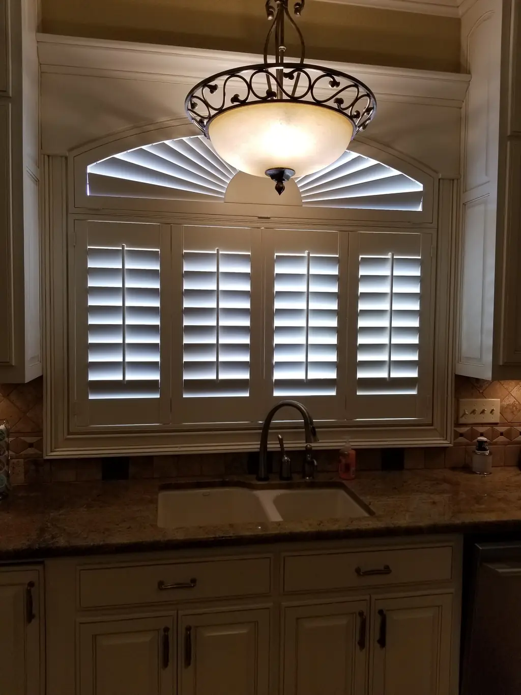 Plantation shutters and a fan transom above a kitchen sink in a Central Arkansas home
